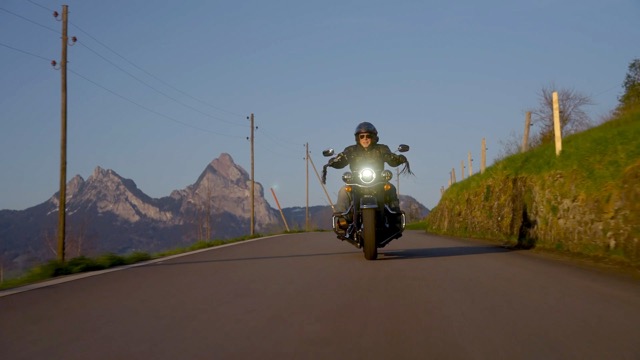 Motorcyclist riding on an open mountain road at sunrise, representing first ride powered by Synhelion renewable gasoline with alpine scenery in the background