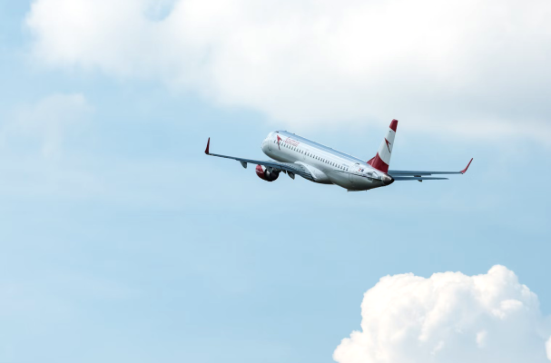 Commercial airplane taking off into a cloudy sky, viewed from behind as it climbs upward.